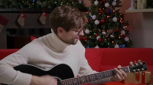 Young Man Playing Guitar at Christmas