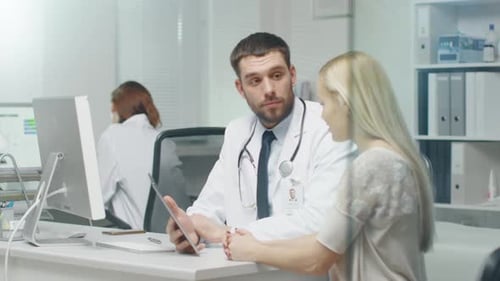 In Doctor's Office Professional Doctor Consults Beautiful Young Woman with a Help of a Tablet. They
