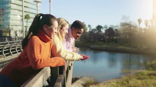 Three Female Friends Talking Near the Lake in the Park During a Sunny Day