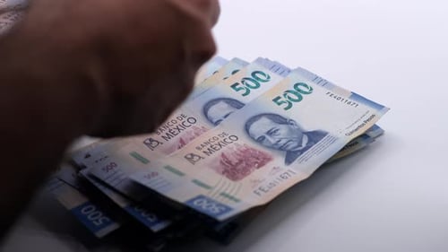 Pessoa contando notas de 500 pesos mexicanos uma a uma