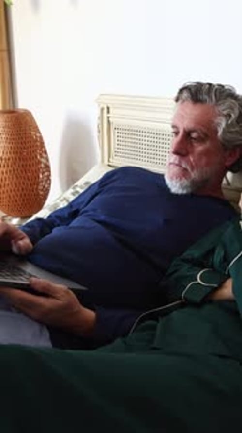 Senior Couple Relaxing in Bed with Laptop