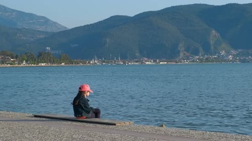 Girl Sitting on Bench by the Ocean