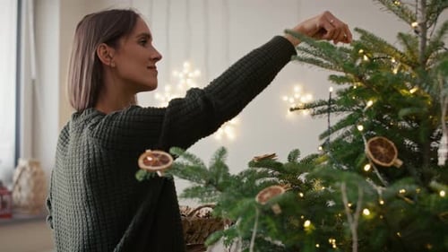 Woman Decorating Christmas Tree with Festive Ornaments