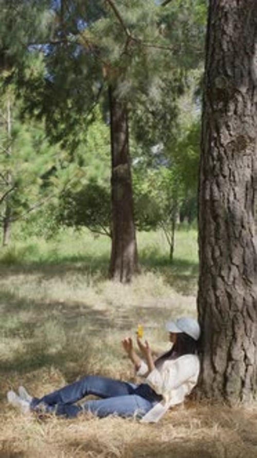 Woman Relaxing Under Tree with Flower in Forest