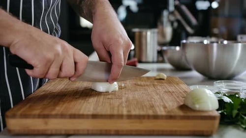 Chef Slicing Onion on Cutting Board in Kitchen