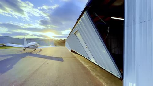 hangar door opens as sun sets, sunset with piper cherokee 180 on tarmac