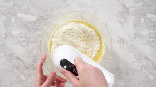 Time Lapse Flat Lay Mixing Ingredients in a Glass Mixing Bowl to Bake Funfettti Bundt Cake