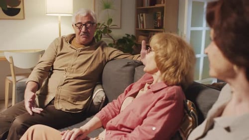 Three Adults Talking on a Couch Indoors