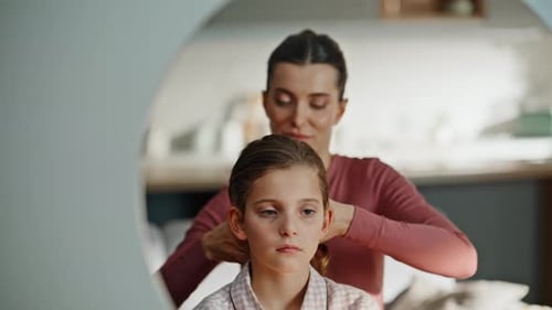 Loving Mother Braids Daughter's Hair in Sunny Home