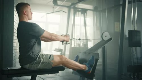Profile Shot of Fit Man Performing Seated Cable Row on Cable Crossover Machine