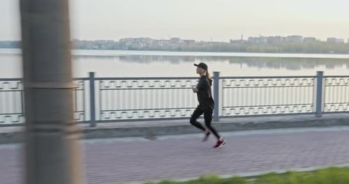 Sportswoman Running on Embankment in Evening
