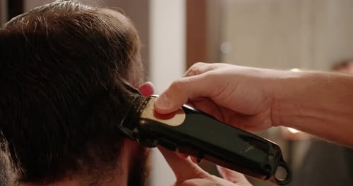 Hübscher Mann bekommt neue Frisur mit elektrischem Trimmer Nahaufnahme mit Trimmer