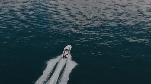 Aerial Zoom Shot of a Boat Sailing to the Blue Sea Moving at High Speed