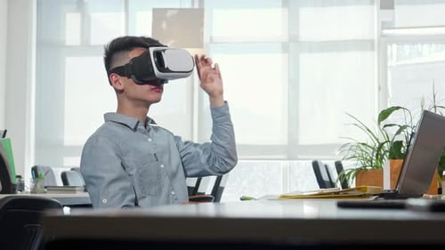 Young Businessman Immersed in Virtual Reality at His Modern Office