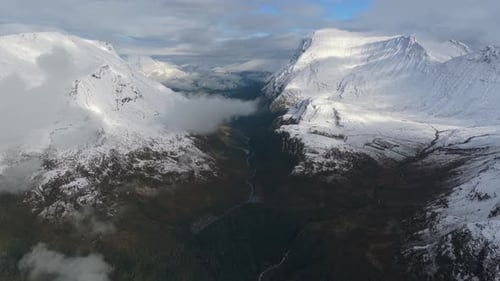 Foto de drone de uma rodovia panorâmica ladeada por picos cobertos de neve, Noruega
