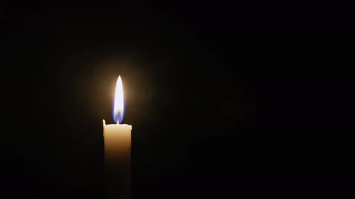 Hand Lighting Candle with Match in Dark Room
