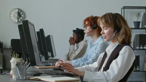 Customer Service Employee Having Conversation with Client and Typing on Keyboard