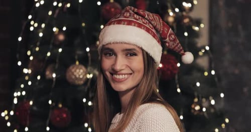 Festive woman smiling in front of Christmas tree