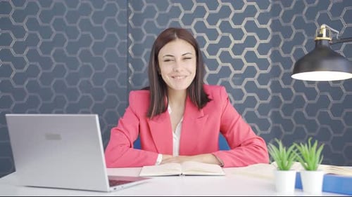 Smiling Woman Sits at Office Desk