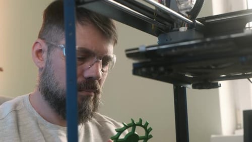 Male Engineer in a Modern Home Office Observing the Printing Process of a 3d Model