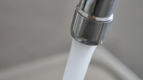 Water Flows From Chrome Faucet in Close-up Shot