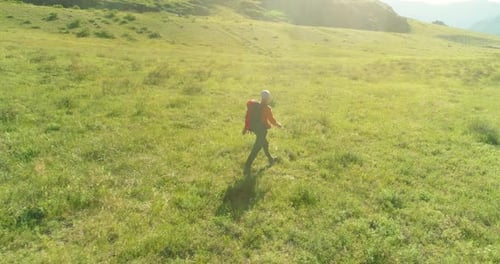 Flight Over Backpack Hiking Tourist Walking Across Green Mountain Field Huge Rural Valley at Summer