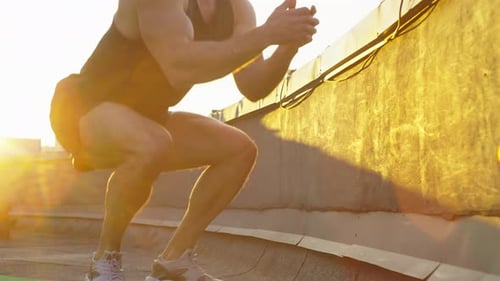 Muscular Man Box Jump Training on Rooftop at Sunset