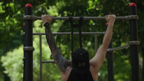 Tattooed Man Doing Pull Ups in Park