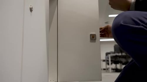 Un individu ouvre un petit casier de rangement personnel dans un environnement de bureau intérieur, plaçant Interna