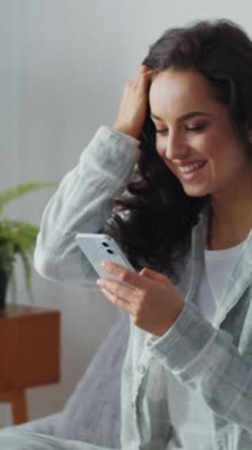 Woman in Pajamas Using Smartphone Indoors in Bedroom