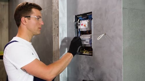 Electrician Inspecting Electrical Panel in Bright Interior