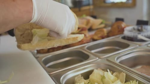 Close up of mans hands putting cabage and making sandwich