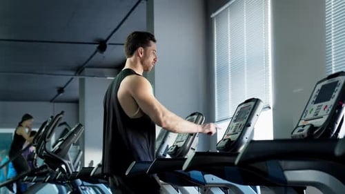 Young Athletic Man Exercising and Walking on Treadmill in Sport Gym