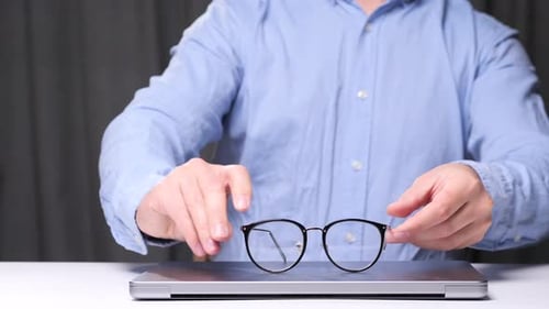 Businessman Placing Eyeglasses on Laptop After Finishing Work Break