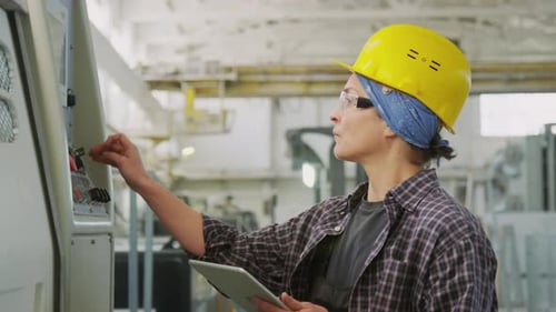 Female Technician Operating Industrial Machine with Digital Tablet
