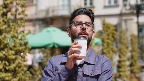 Young Indian Man Enjoying Drinking Morning Coffee Hot Drink Relaxing Taking a Break in City Street