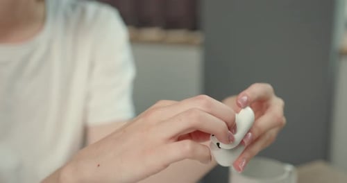 Woman Holding Wireless Earbuds and Charging Case