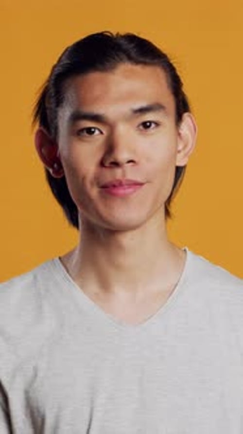 Vídeo vertical, alegre, sorridente, posando em fundo laranja