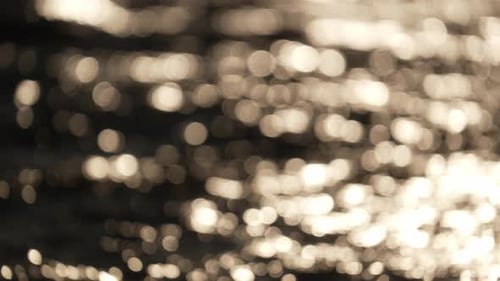 Bokeh (blurry) shot of moving ocean surface at golden sunset; artistic concept