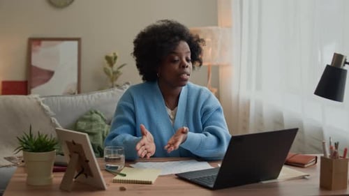 Female Freelancer Talking on Video on Laptop in Cozy Home Office