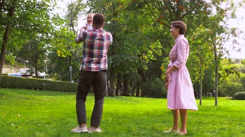 Happy young family playing together and flying a toy airplane at the park in summer