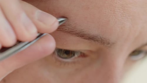 Person Plucking Eyebrows with Tweezers Close Up