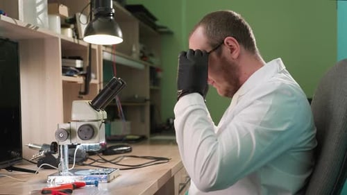 Technician Repairs Electronics with Microscope in Lab