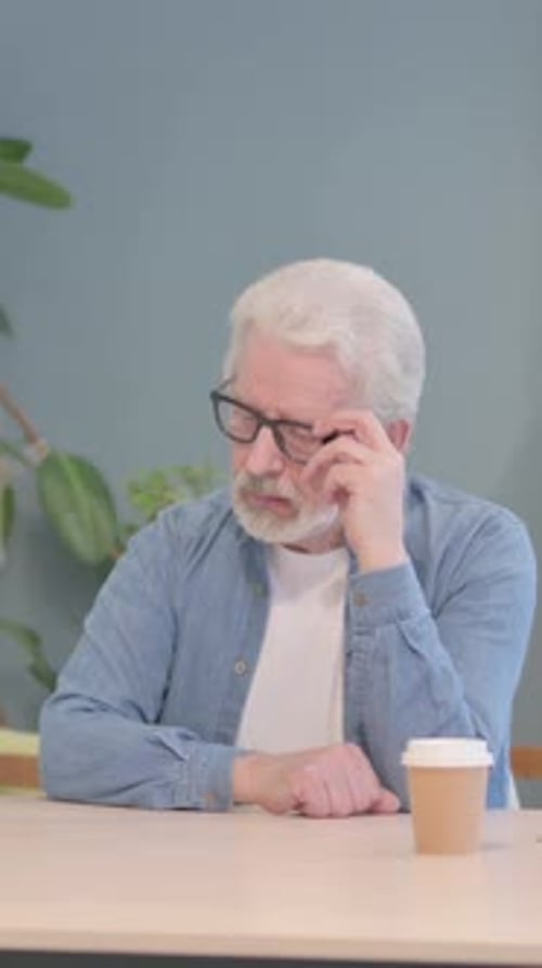 Thoughtful Senior Man Sitting at Table Thinking