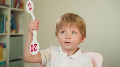 Boy Holding Number Paddle in Classroom Setting