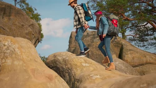 Adventurous Happy Young Man and Woman Climbing on Clifftop Observing Scenery of Stone Rocks and Wild