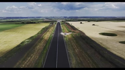 Long Paved Highway Running to Horizon Among Fields Aerial View