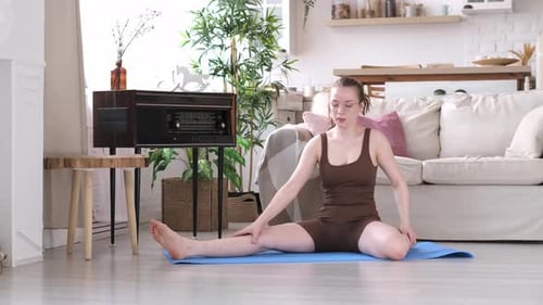 Woman Doing Stretching Exercises on Yoga Mat at Home