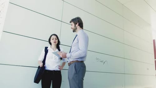 Young Businessman and Businesswoman with Tablet Outside in City, Talking