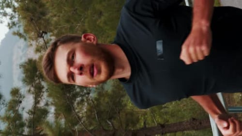 Portrait of young man running in forest. Vertical video